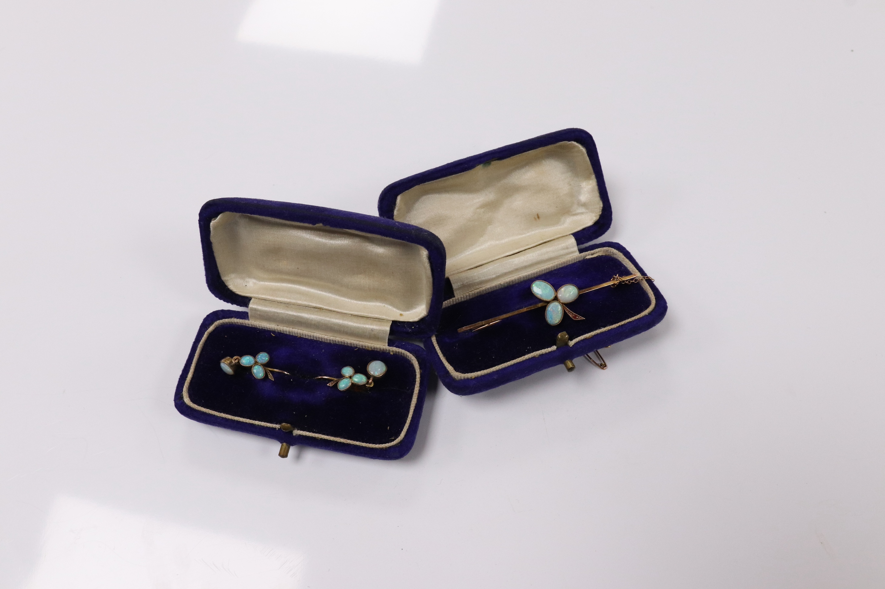 A 9ct and three stone white opal and single stone ruby set bar brooch, 58mm, together with a pair of yellow metal and opal cluster set earrings. Condition - fair